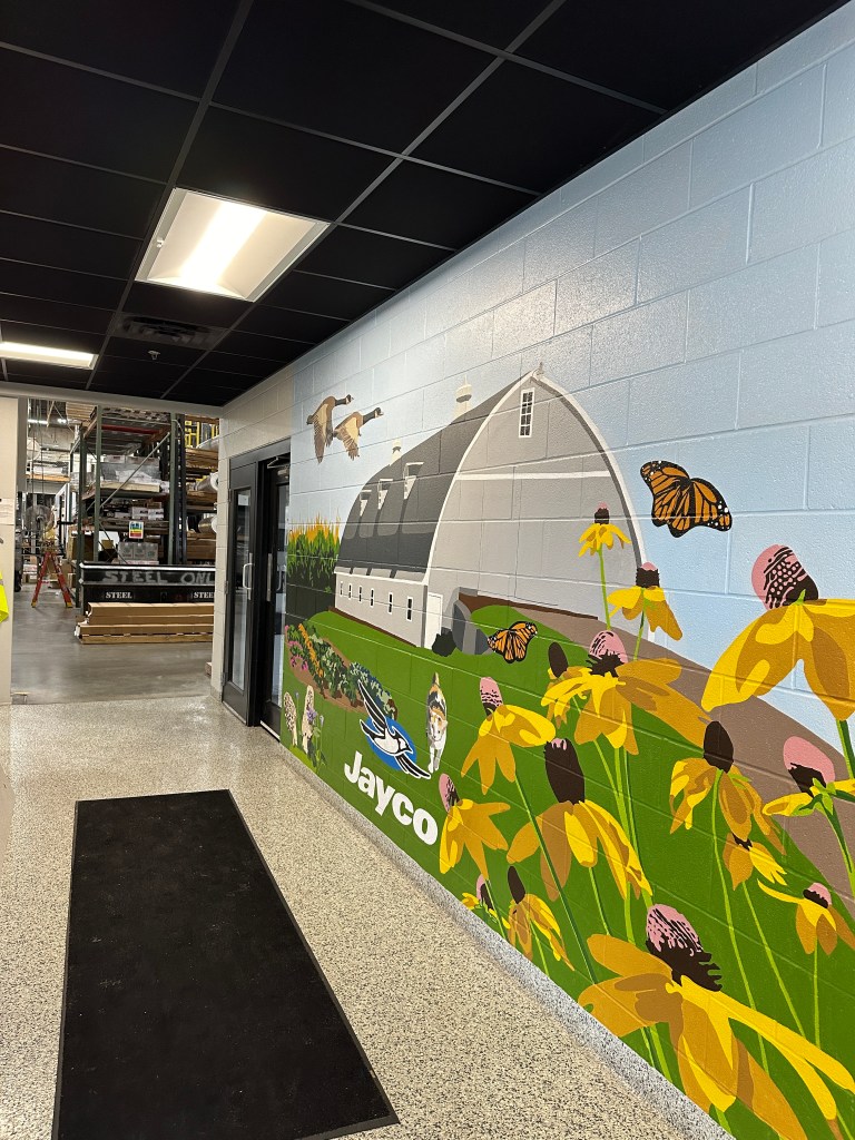 A hand painted custom mural that depicts a midwestern barn where a manufacturing company first began